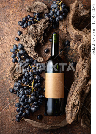 Bottle of red wine with blue grapes and old weathered snags. 121433386