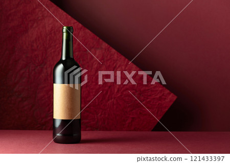 Bottle of red wine on a red background. 121433397