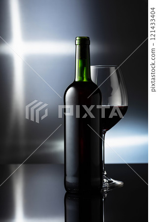 Glass and bottle of red wine on a black reflective background. 121433404