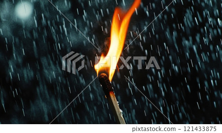 Matchstick burning brightly amidst falling rain on a dark background 121433875