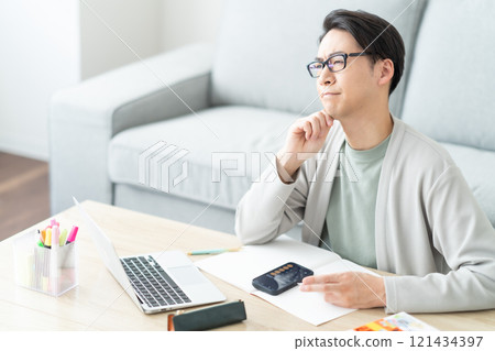 A young man struggling to sort his tax return A young man struggling to sort his tax return 121434397