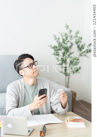 一名年輕人一邊查看收據一邊整理分類帳費用 121434403