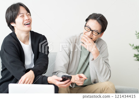 Young men chatting while looking at their smartphones 121434415