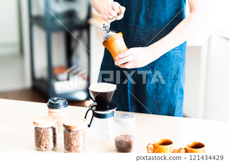 A middle-aged female store clerk carefully grinds coffee beans 121434429