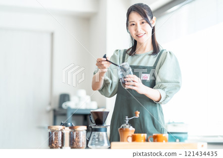 A middle-aged woman pouring coffee beans into a dripper at a cafe A middle-aged woman pouring coffee beans into a dripper at a cafe 121434435