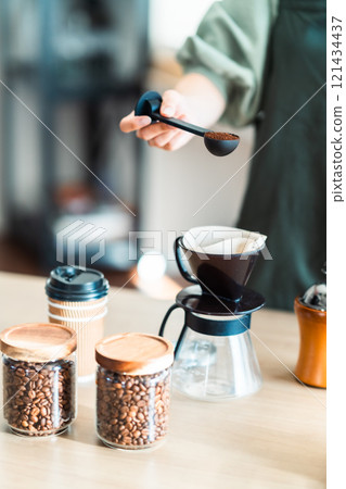 Female store clerk measuring drip coffee with a spoon (no face) Female store clerk measuring drip coffee with a spoon (no face) 121434437