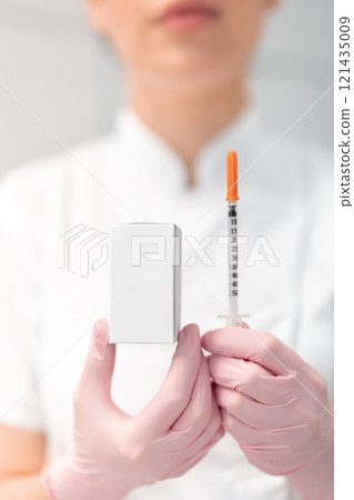 Female dermatologist holding injection syringe and 121435009