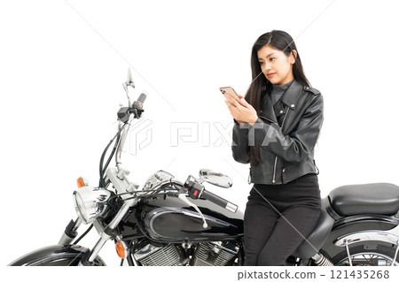 A young woman sitting on a motorcycle and looking at a map on her smartphone A young woman sitting on a motorcycle and looking at a map on her smartphone 121435268