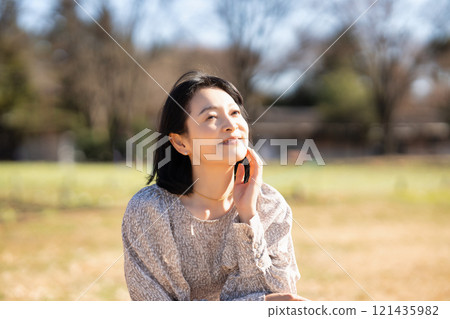 Middle-aged woman relaxing on the grass in the park 121435982