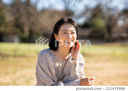 Middle-aged woman relaxing on the grass in the park Middle-aged woman relaxing on the grass in the park 121435986
