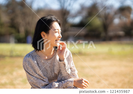 Middle-aged woman relaxing on the grass in the park 121435987