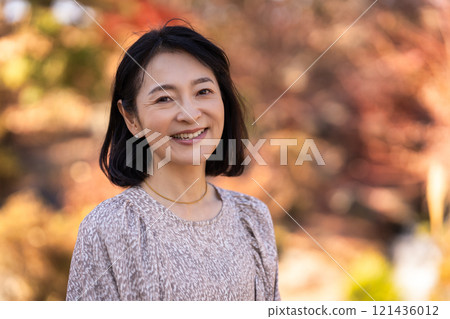 走在秋天公園的微笑的中年婦女 121436012