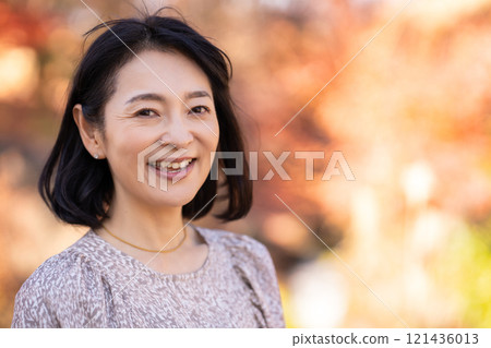 A smiling middle-aged woman strolling through an autumn park A smiling middle-aged woman strolling through an autumn park 121436013