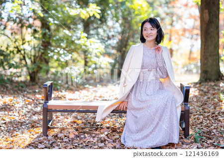 中年婦女坐在充滿自然的公園的長凳上 121436169