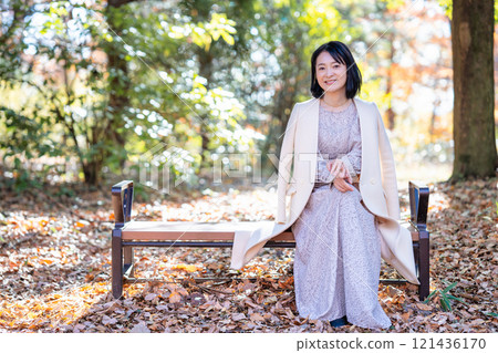 中年婦女坐在充滿自然的公園的長凳上 121436170