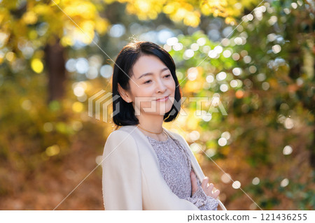 A middle-aged woman strolling through a forest park rich in nature A middle-aged woman strolling through a forest park rich in nature 121436255