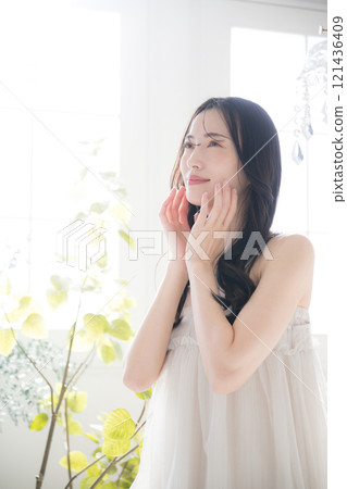 A beauty image of a young woman with beautiful bare skin against the backlight and greenery by the window 121436409