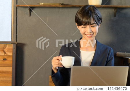 一位女士在咖啡館喝咖啡時看著電腦 一位女士在咖啡館喝咖啡時看著電腦 121436470