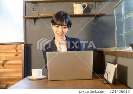 A woman working on a computer in a cafe 121436613
