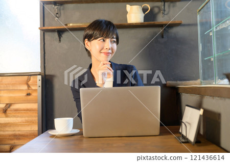 A woman working on a computer in a cafe A woman working on a computer in a cafe 121436614