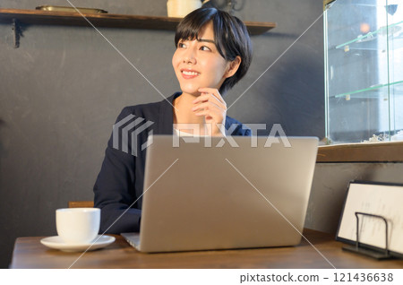 一名在咖啡館使用電腦工作的女士 一名在咖啡館使用電腦工作的女士 121436638