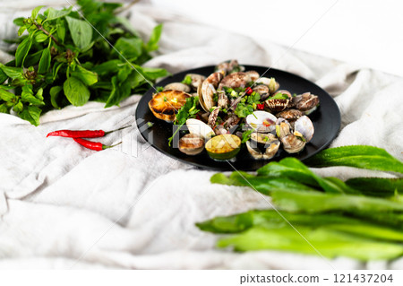 Fresh seafood platter features garlic clams and mussels alongside vibrant herbs and chili. 121437204