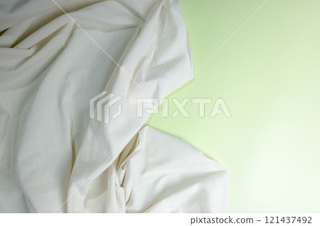 Top view of crumpled white fabric on a colored background Top view of crumpled white fabric on a colored background 121437492