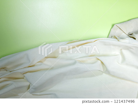 Top view of crumpled white fabric on a colored background Top view of crumpled white fabric on a colored background 121437496
