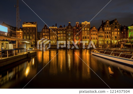 Panoramic view of facades of colorful illuminated Amsterdam houses reflecting in the river canal with night scene background 121437504