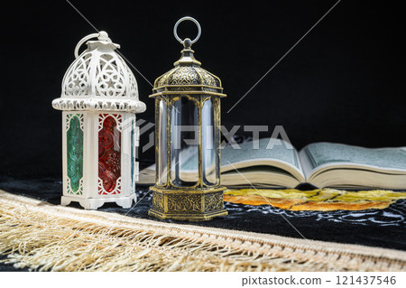 Arabic lanterns and Quran on a prayer mat with a black background. Decoration for Muslim holidays celebration Arabic lanterns and Quran on a prayer mat with a black background. Decoration for Muslim holidays celebration 121437546