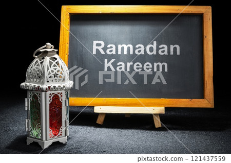 Wooden easel and chalkboard with the text of Ramadan Kareem and Arabic lantern on a black background 121437559