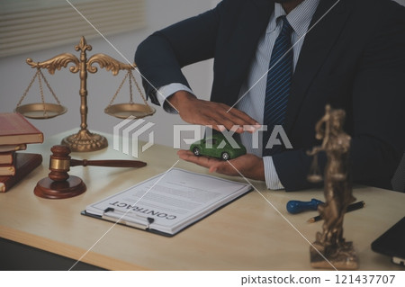 Judge gavel and miniature car symbolize auction or court case against driver who has accident and receiving vehicle insurance payment be on table in front of hands of lawyers. Selective focus 121437707