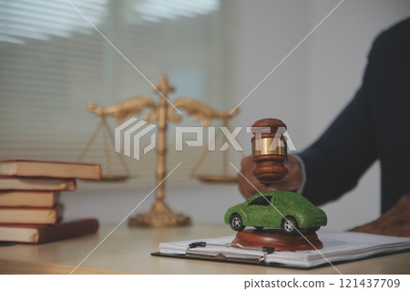 Judge gavel and miniature car symbolize auction or court case against driver who has accident and receiving vehicle insurance payment be on table in front of hands of lawyers. Selective focus Judge gavel and miniature car symbolize auction or court case against driver who has accident and receiving vehicle insurance payment be on table in front of hands of lawyers. Selective focus 121437709