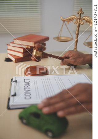 Judge gavel and miniature car symbolize auction or court case against driver who has accident and receiving vehicle insurance payment be on table in front of hands of lawyers. Selective focus Judge gavel and miniature car symbolize auction or court case against driver who has accident and receiving vehicle insurance payment be on table in front of hands of lawyers. Selective focus 121437711