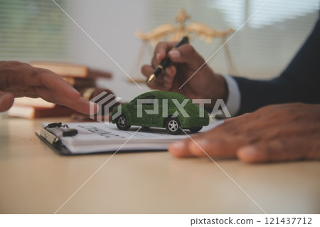 Judge gavel and miniature car symbolize auction or court case against driver who has accident and receiving vehicle insurance payment be on table in front of hands of lawyers. Selective focus 121437712