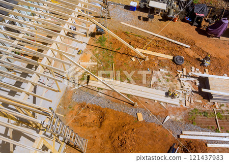 Workers are engaged in building framework structure with wooden beams while tools, materials are scattered around on construction work area Workers are engaged in building framework structure with wooden beams while tools, materials are scattered around on construction work area 121437983