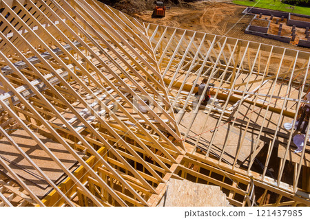 Workers are framing roof using wooden materials at busy construction site in work area. Workers are framing roof using wooden materials at busy construction site in work area. 121437985