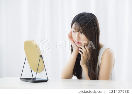一位年輕女子照鏡子，擔心自己的皮膚 121437988