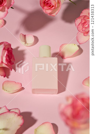 Top shot photography for pink rose product advertisement. A cosmetic mock up bottle in pink color flat lay on soft pink countertop, surrounded by fresh pink rose flowers and petals Top shot photography for pink rose product advertisement. A cosmetic mock up bottle in pink color flat lay on soft pink countertop, surrounded by fresh pink rose flowers and petals 121438313
