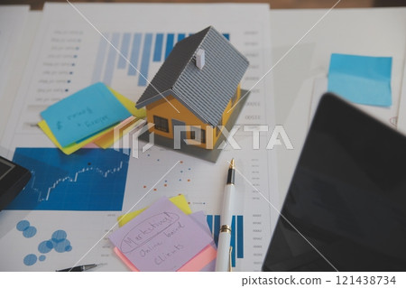Wooden table with laptop, house keys Clipboard with pen, house model and green tree calculator, real estate concept. close up pictures 121438734