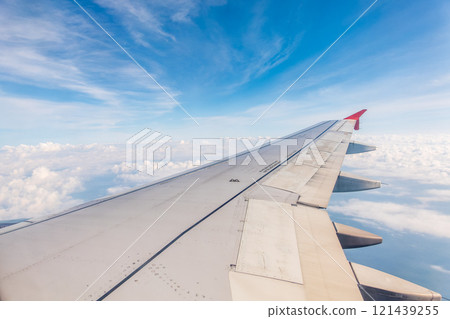 View from the airplane window at a beautiful cloudy sky and the airplane wing 121439255