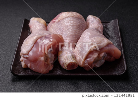 Raw chicken legs with salt, spices and herbs on a dark concrete background 121441981