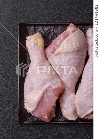 Raw chicken legs with salt, spices and herbs on a dark concrete background 121441982