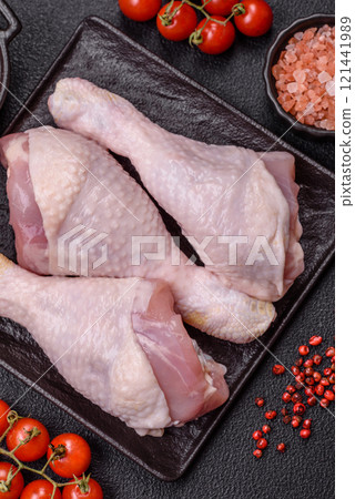 Raw chicken legs with salt, spices and herbs on a dark concrete background Raw chicken legs with salt, spices and herbs on a dark concrete background 121441989