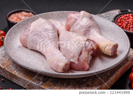 Raw chicken legs with salt, spices and herbs on a dark concrete background Raw chicken legs with salt, spices and herbs on a dark concrete background 121441999