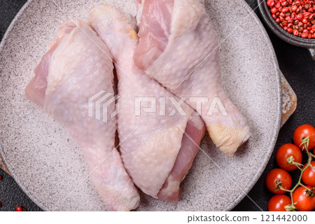 Raw chicken legs with salt, spices and herbs on a dark concrete background 121442000
