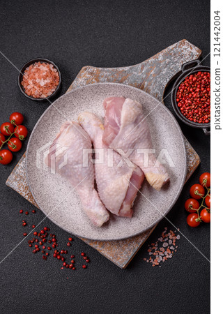 Raw chicken legs with salt, spices and herbs on a dark concrete background 121442004