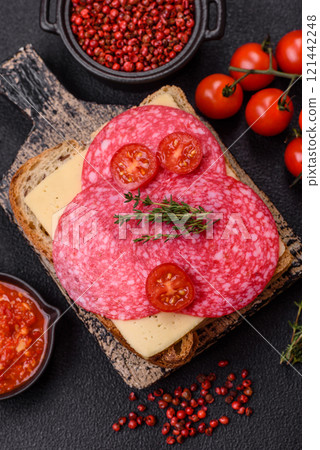 Sandwich with toast, salami slices, cheese and tomatoes, salt and spices 121442248
