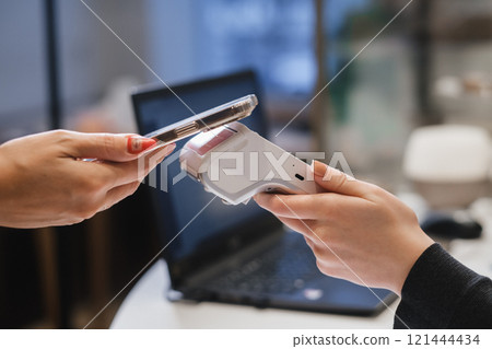 A customer uses his phone to pay through a terminal . Concept of cashless technologies and money transfers 121444434