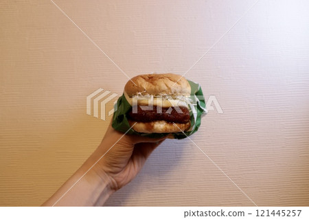 Left hand holding a teriyaki cutlet burger Left hand holding a teriyaki cutlet burger 121445257